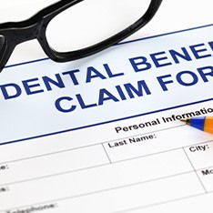 Black-framed glasses on a blue “Dental Benefits Claim Form”