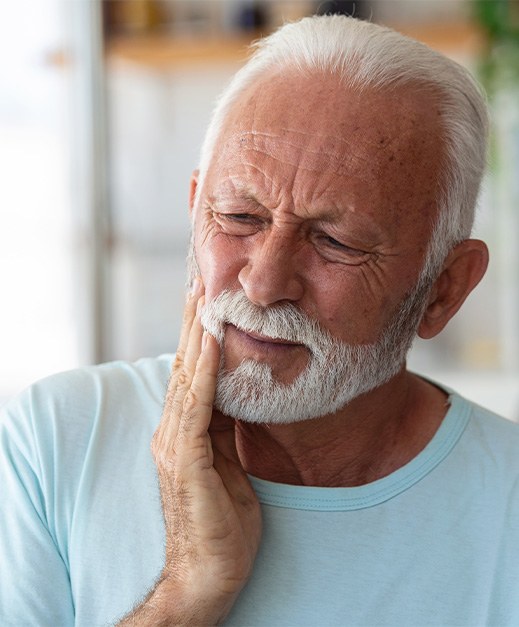 Bearded man with tooth pain rubbing his jaw