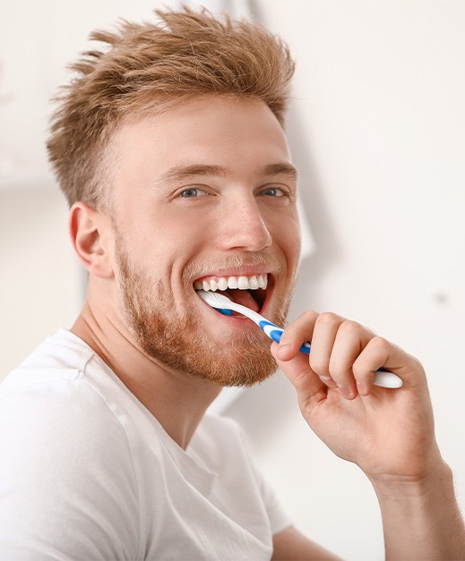 Smiling man brushing his teeth