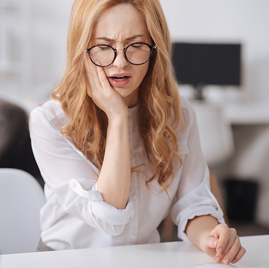 Woman in white shirt needing an emergency dentist in Columbus, NJ