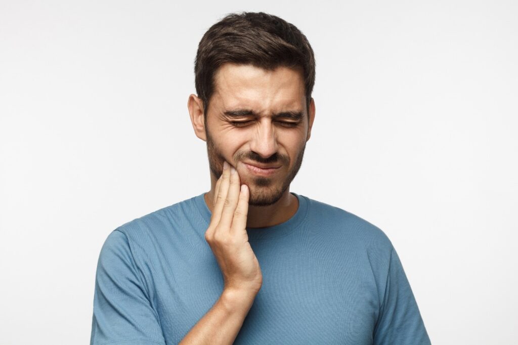 person with tooth sensitivity holding their cheek