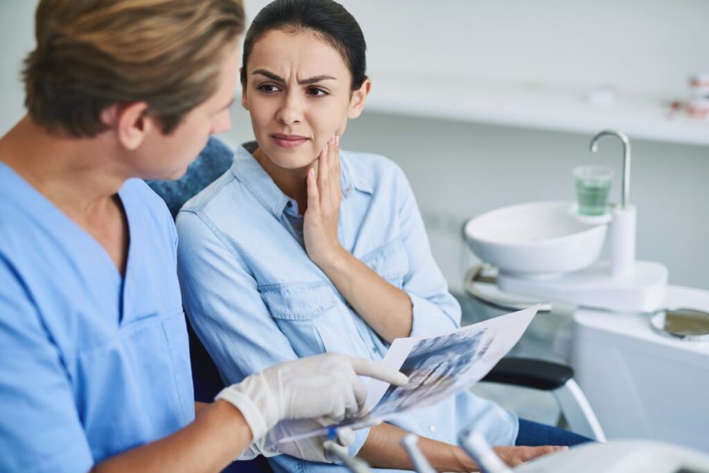 A woman at the dentist holding her jaw in pain.