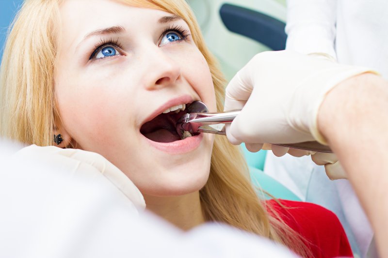 A dentist performing a tooth extraction on a woman